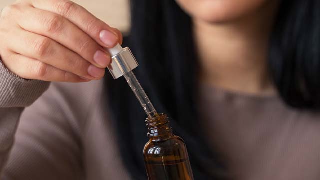 A lady holding a bottle of hair oil