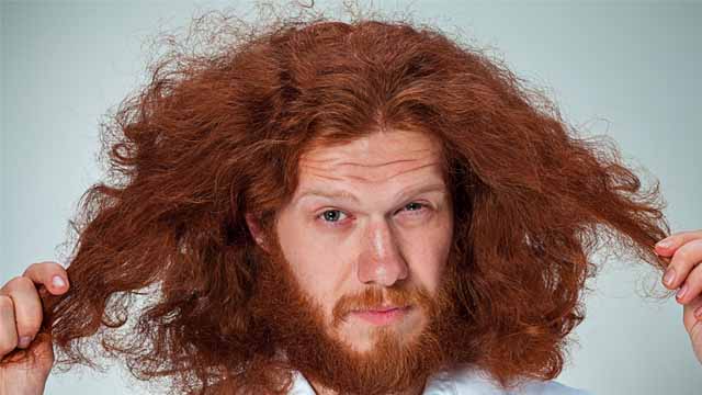A ginger haired man pondering abou the texture of his hair